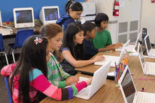 Niños usando computadoras en un salón de clases